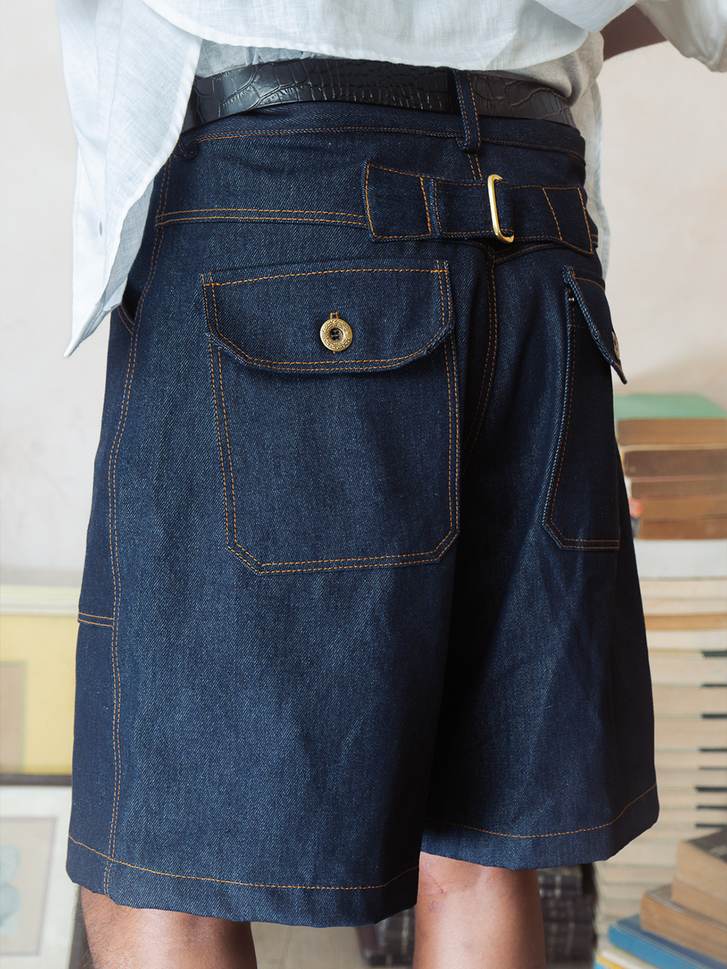 Person wearing a pair of indigo tous denim shorts with a belt.