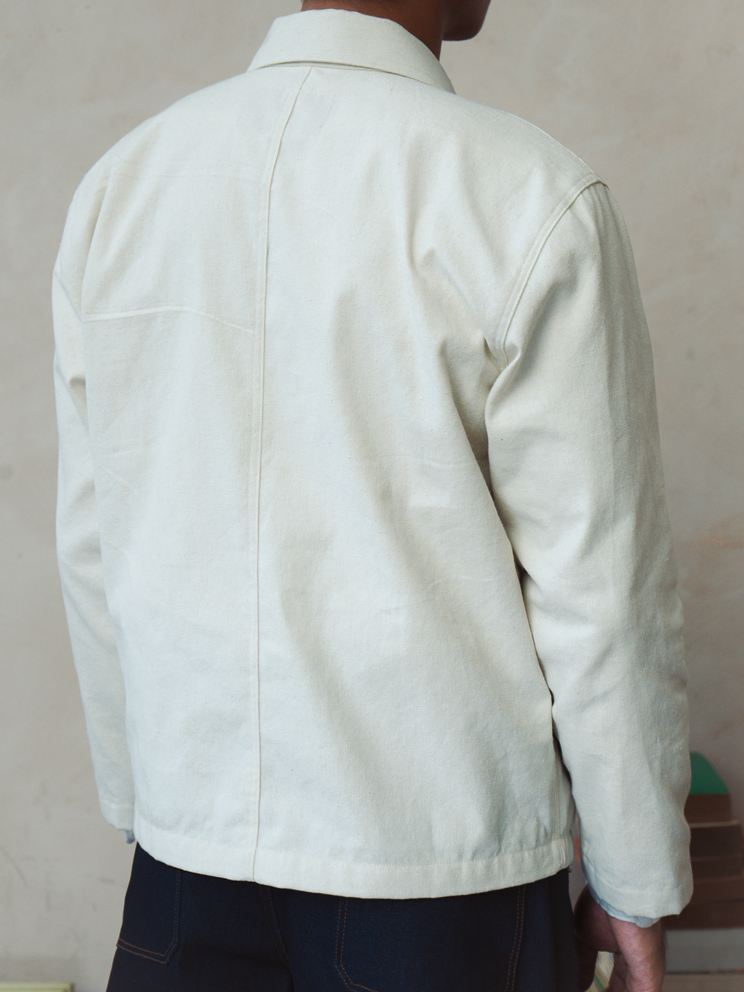Person wearing a white french chore jacket with a neutral background