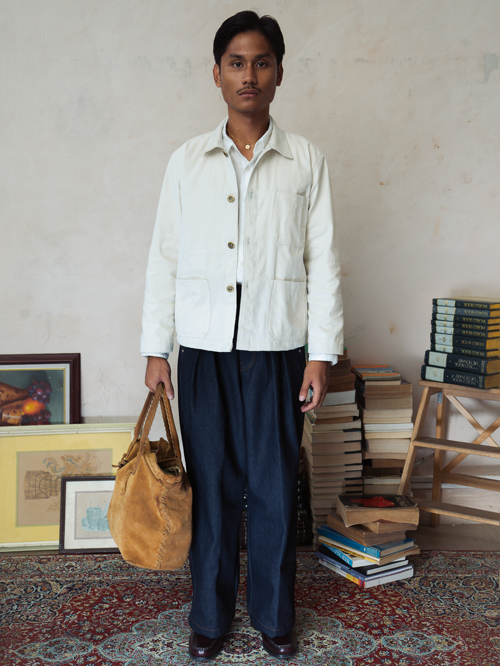 Person holding a brown bag in a room with books and artwork on a patterned rug.