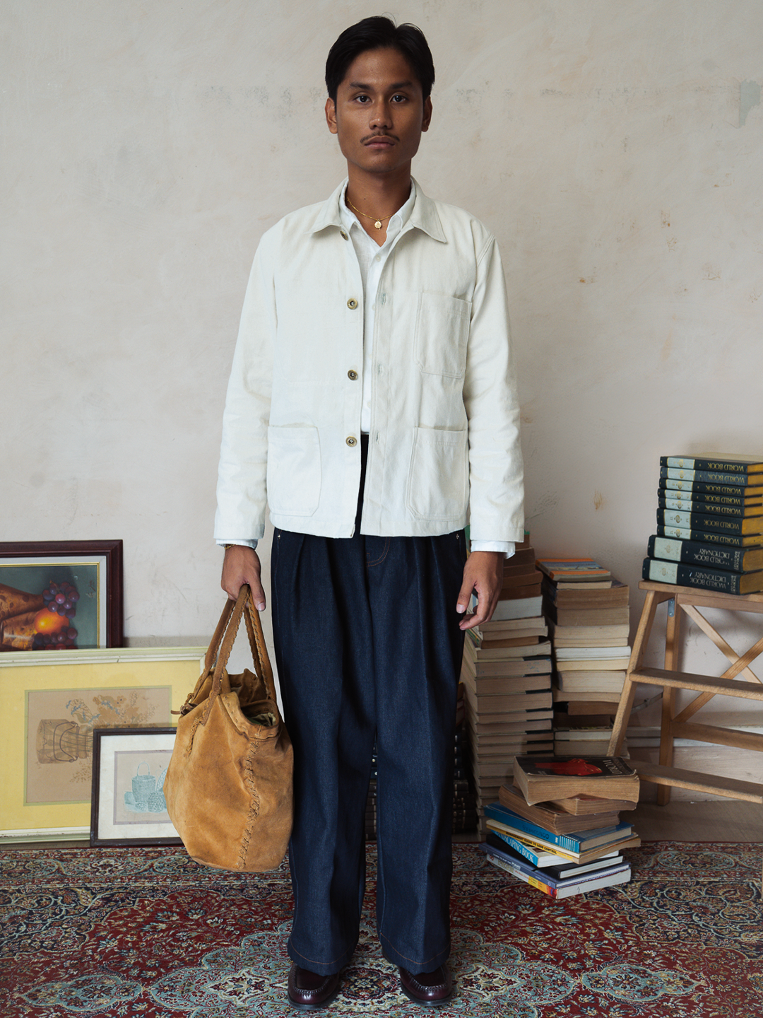 Person holding a brown bag in a room with books and artwork on a patterned rug.