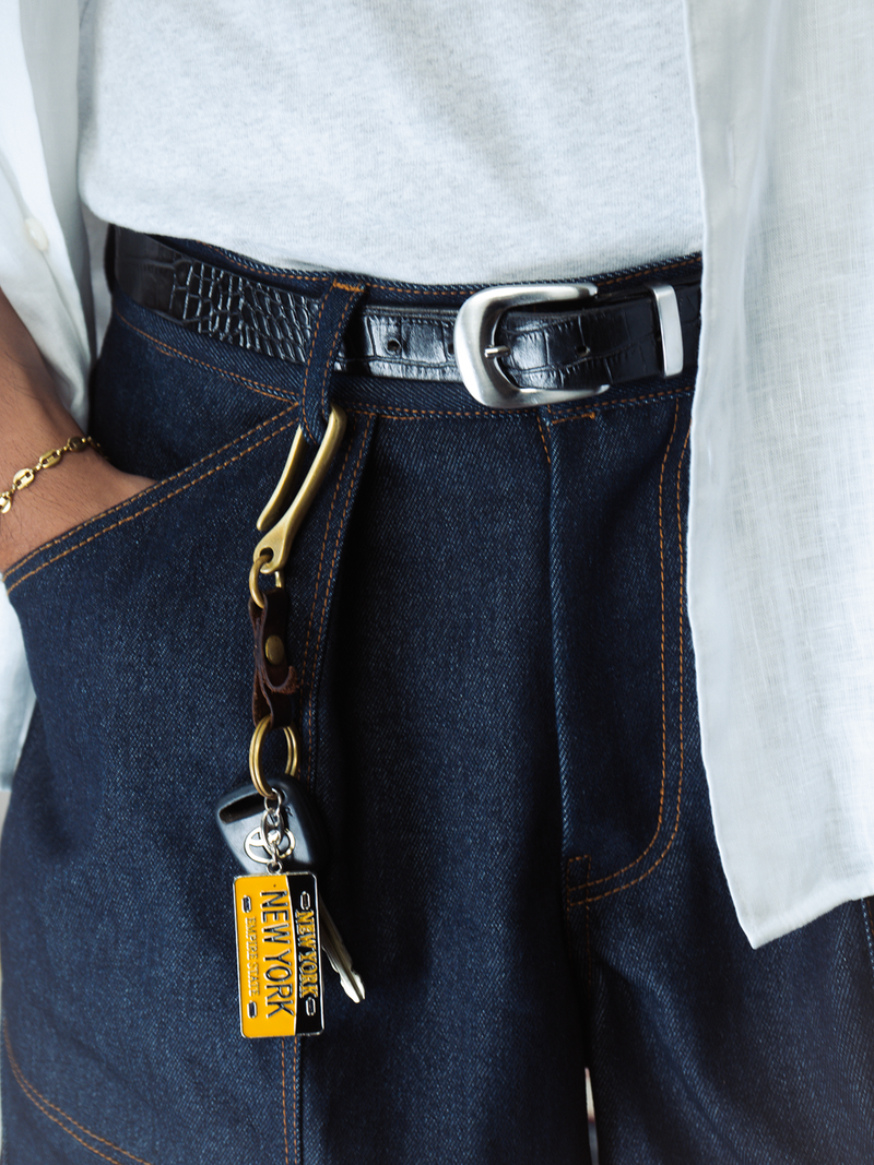 Close-up of a person wearing indigo denim shorts with a keychain and belt buckle.