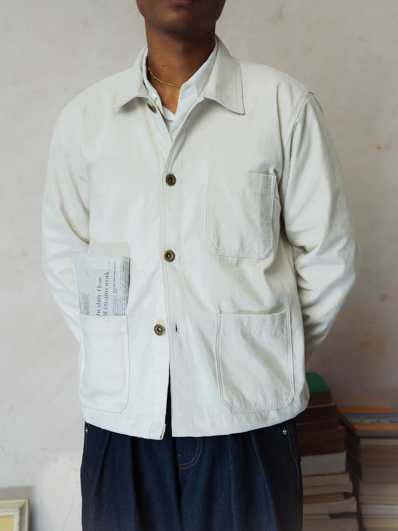 Person wearing a tous cream chore jacket with buttons against a neutral background