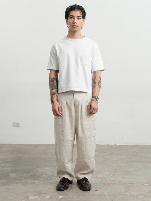 Person wearing a white t-shirt and cream medium weight linen gurkha pants standing against a plain background