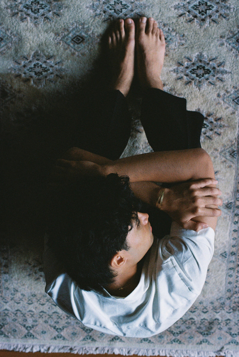 Person lying on a patterned rug with arms crossed