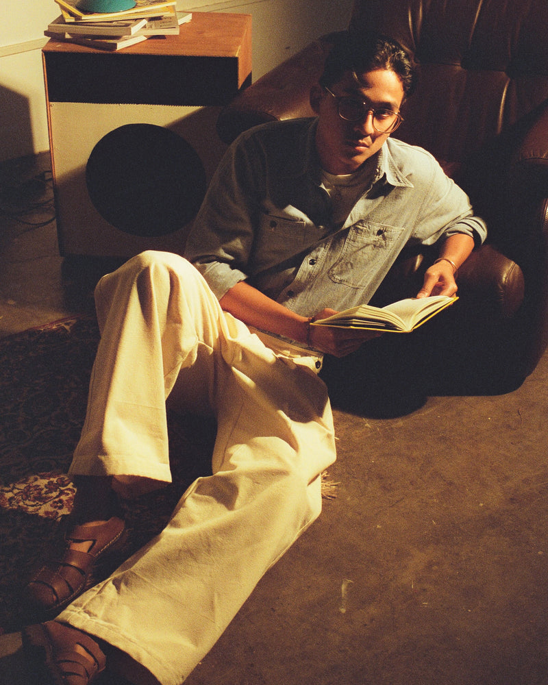 Person sitting on a couch reading a book in a dimly lit room.