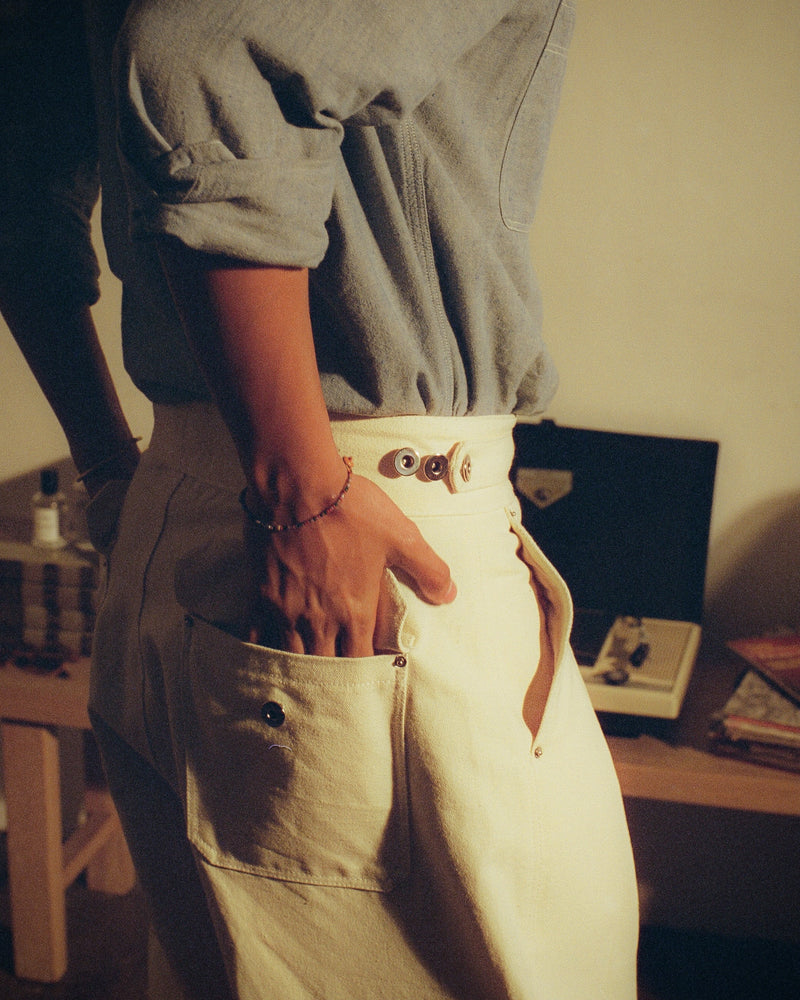 Person wearing a pair of tous cream canvas gurkha pants reaching his back pocket. 