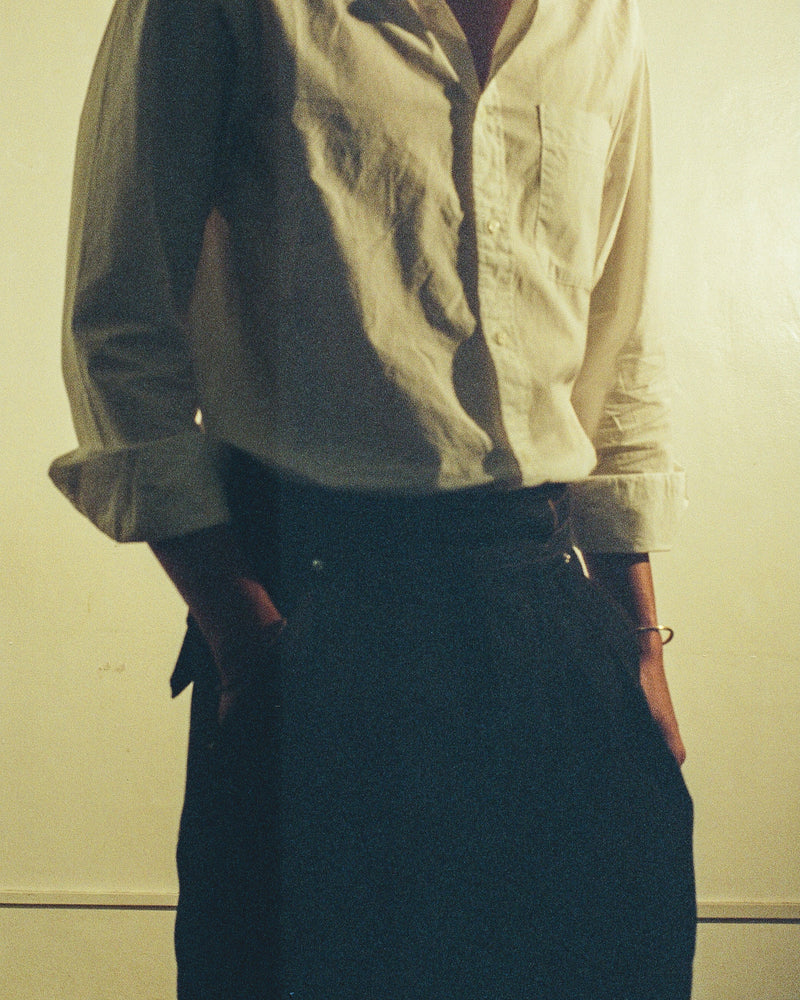 Person wearing a light-colored shirt and tous denim gurkha pants against a plain background