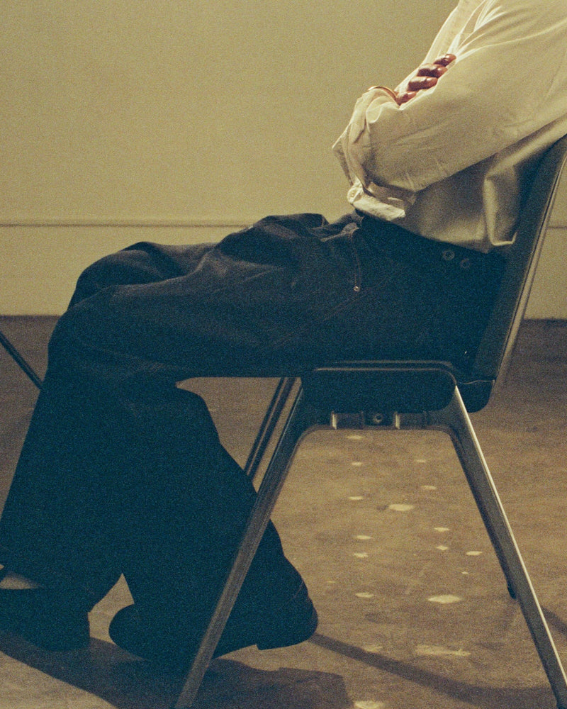 Person sitting on a chair with legs crossed in a room.