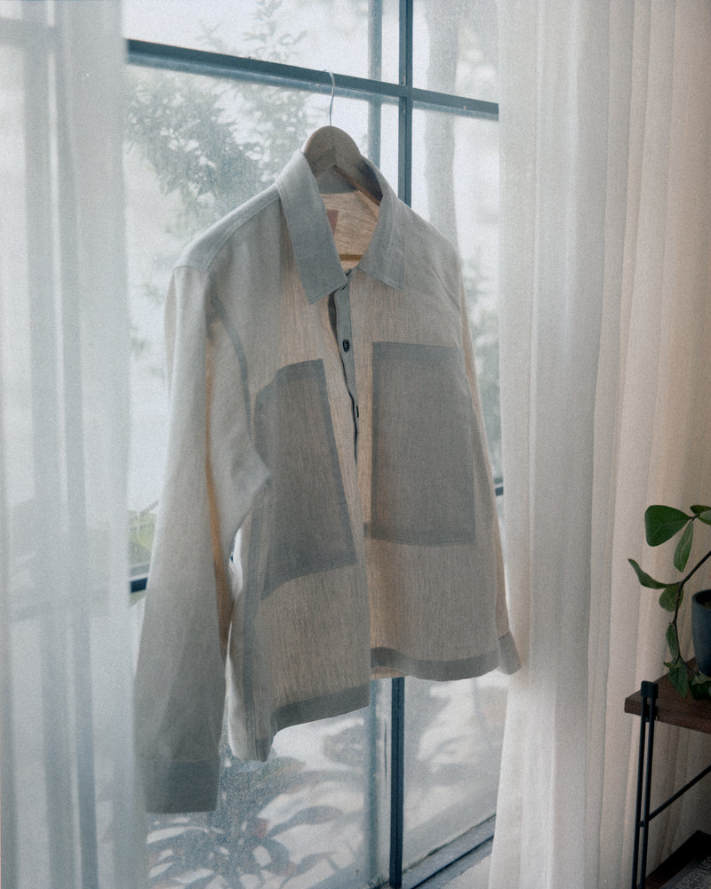 A tous cream linen pullover shirt with sheer curtains in the background