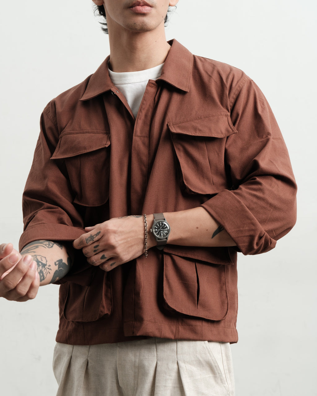 Person wearing a brown linen jungle jacket and linen medium weight linen gurkha shorts with a white background