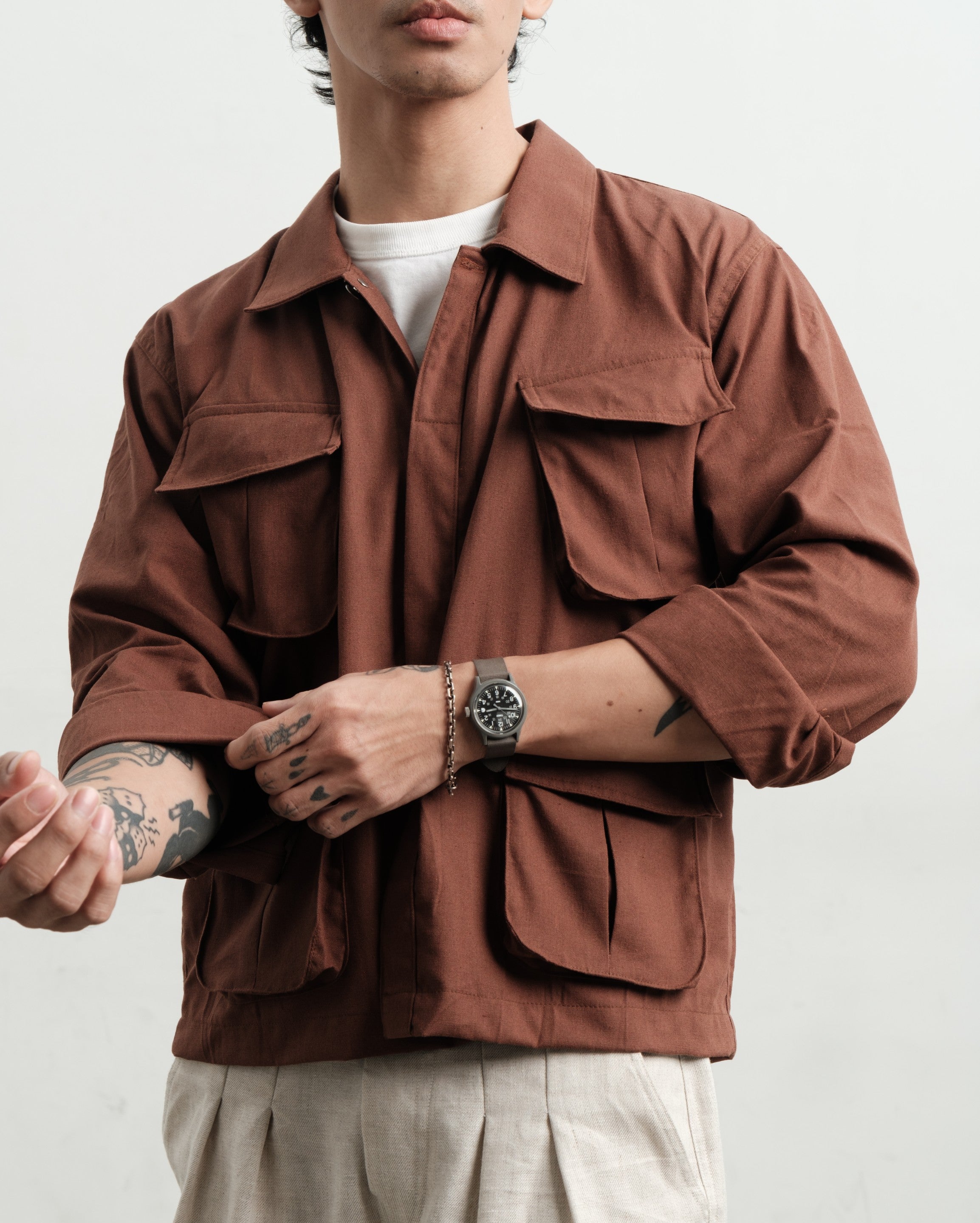 Person wearing a brown linen jungle jacket and linen medium weight linen gurkha shorts with a white background