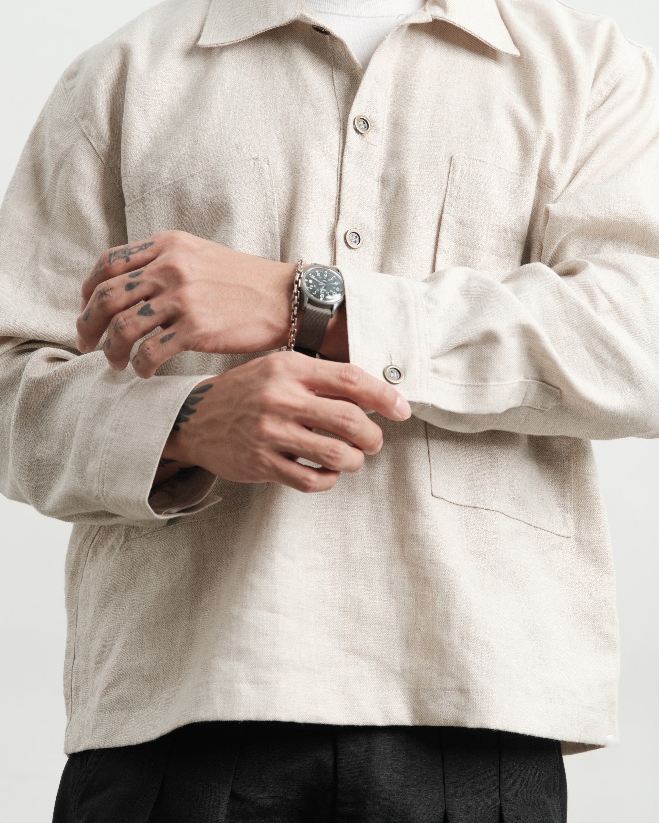 Person wearing a medium weight linen pullover shirt, adjusting cuffs with a vintage century watch.