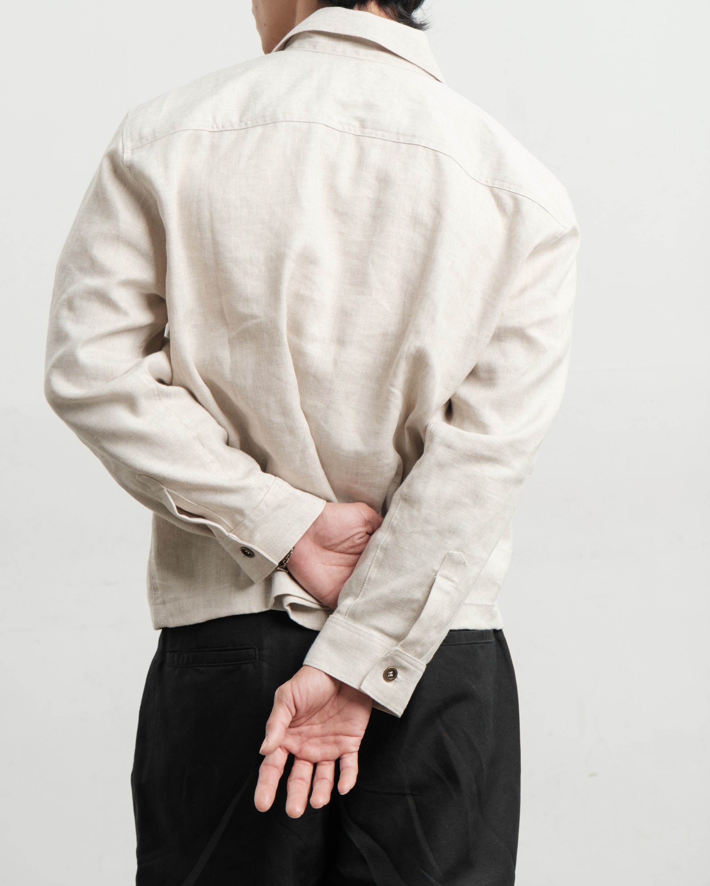 Person wearing a medium weight linen pullover shirt black linen gurkha pants on a plain background